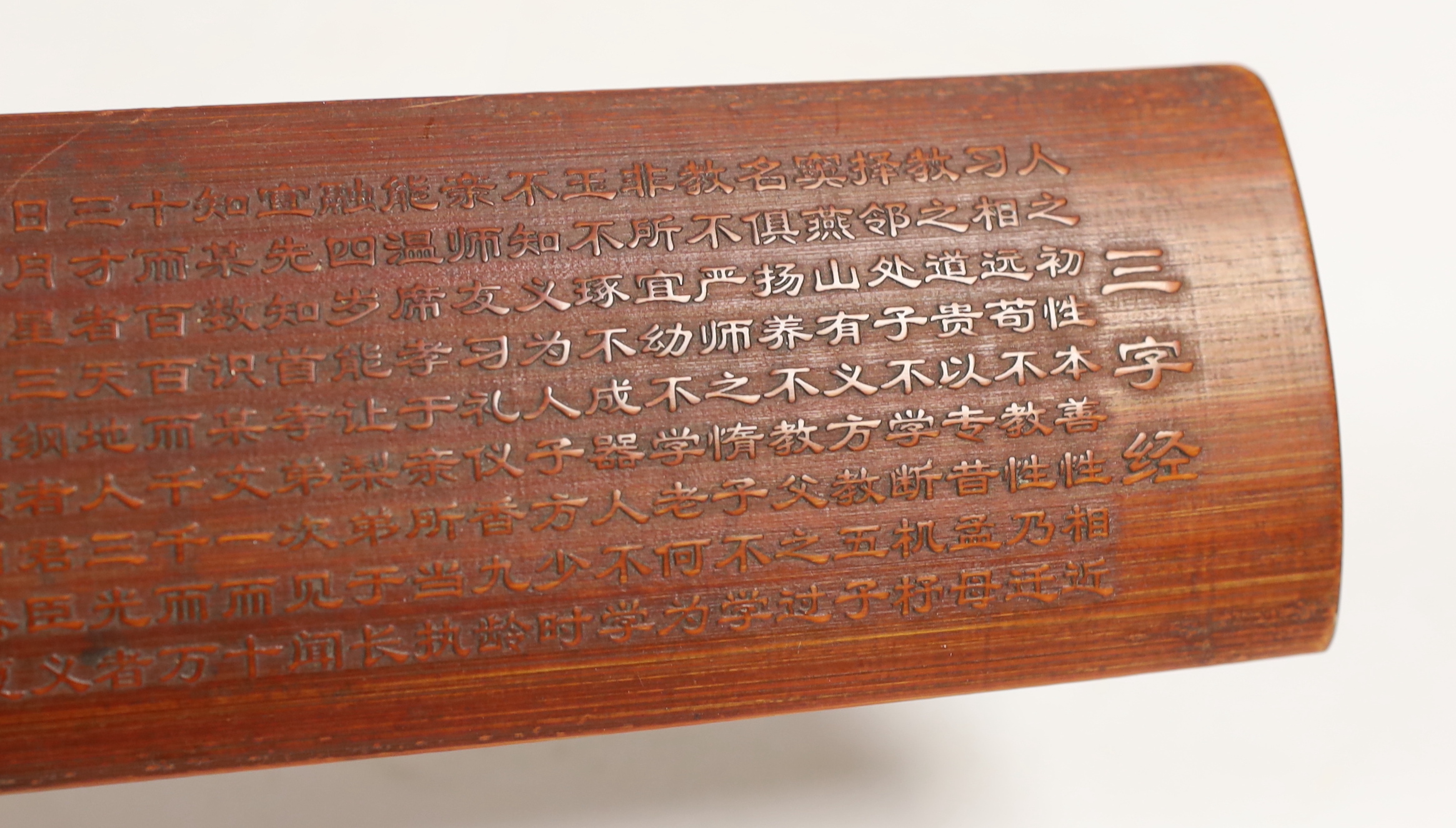 A Chinese bamboo inscribed wrist rest, carved in relief with columns of calligraphy, 30cm wide